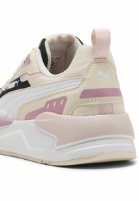 Sportskor med en överdel i krämfärgad och svart textil, rosa detaljer och vit mellansula. Utmärkande hälflik och strukturerad gummiyttersula.