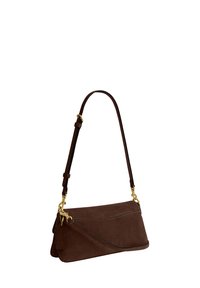 Sac à épaule en daim marron avec quincaillerie dorée, sangle réglable et petite étiquette attachée sur fond blanc.