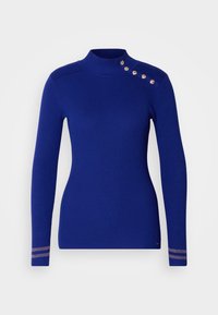Pull bleu en maille côtelée avec un col montant et des boutons dorés en détail sur l'épaule. Présente des accents rayés sur les poignets.