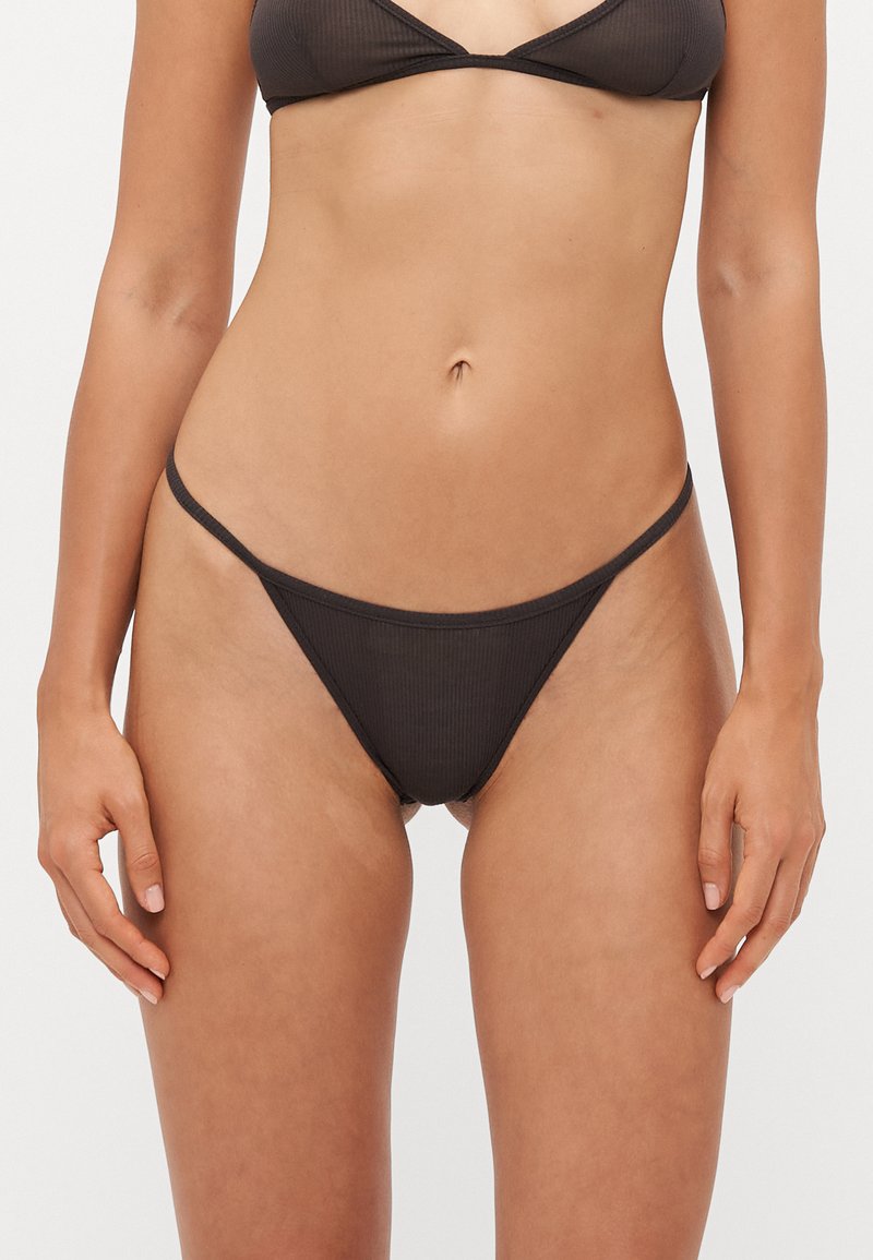 Completo bikini nero a coste, composto da un reggiseno triangolare con spalline sottili e uno slip a perizoma con copertura minima. Tessuto morbido al tatto.