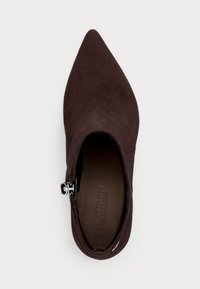 Zapato de ante marrón con punta afilada, cremallera lateral y logo embosado en la plantilla. Textura suave y diseño elegante para un look ajustado.