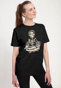 T-shirt nera con un design di uno scheletro dai tratti facciali dettagliati, circondato da rose, con un banner che recita "MAMA SA COSA È MEGLIO."