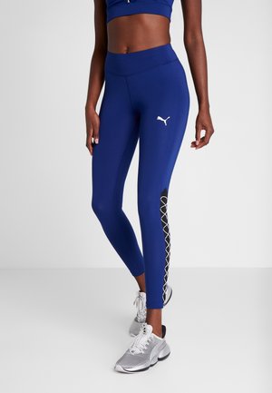 Niebieskie legginsy wykonane z elastycznego materiału z wysokim stanem. Posiadają czarny boczny panel z białym wzorem geometrycznym. Logo Puma z przodu.