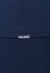 Granatowy top sportowy z prążkowanym teksturem, dopasowanym krojem i widoczną białą etykietą "SMILODOX" na dolnym szwie.