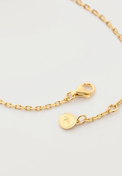 Χρυσό κολιέ με αλυσίδα, κούμπωμα αστακού και μικρή στρογγυλή ταυτότητα με χαραγμένο μινιμαλιστικό σχέδιο σε λευκό φόντο.