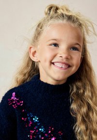Pull en bleu marine avec une texture moelleuse, orné de sequins multicolores en rose et bleu disposés en motif sur le devant.