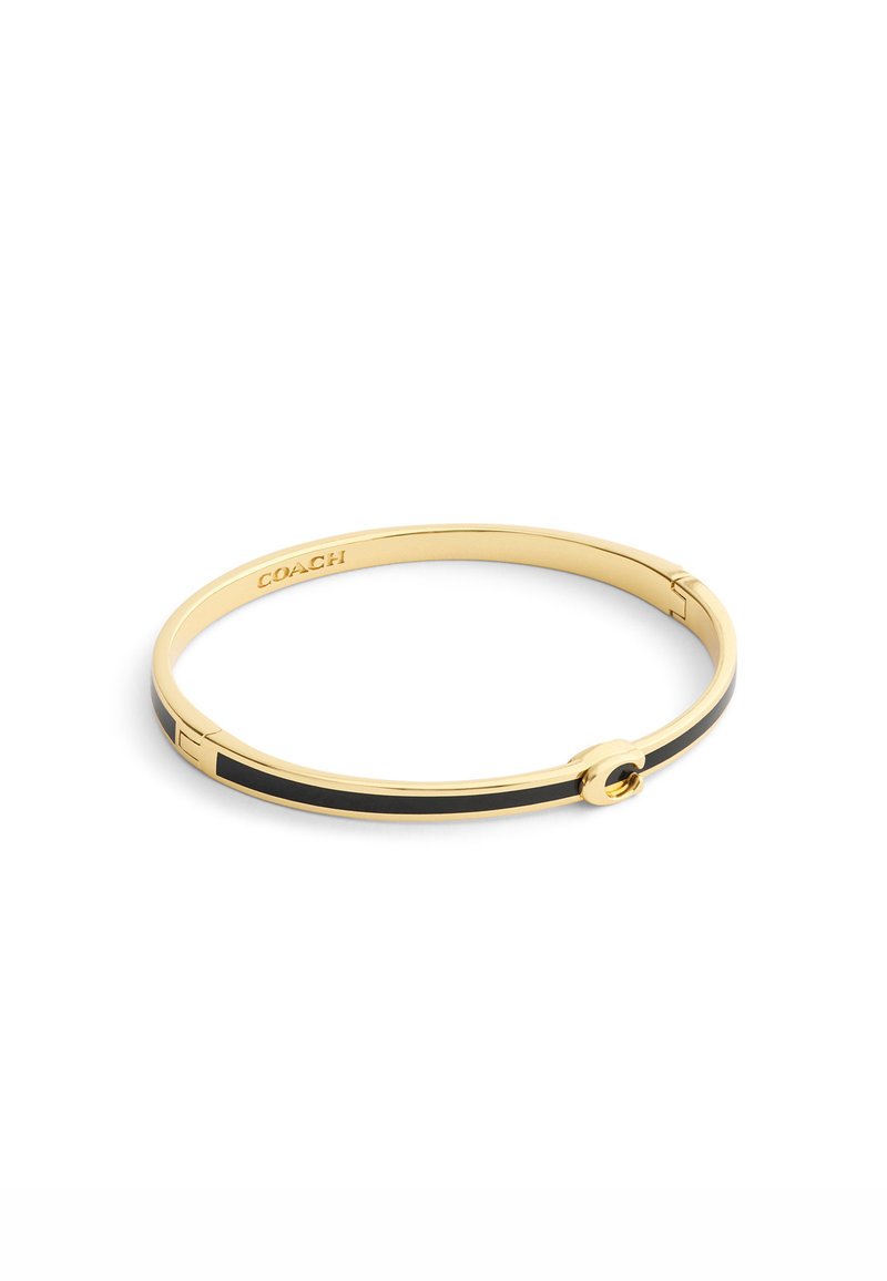 Bracelet jonc doré avec une bande en émail noir et un fermoir circulaire. Présente le nom de la marque gravé sur le côté intérieur.