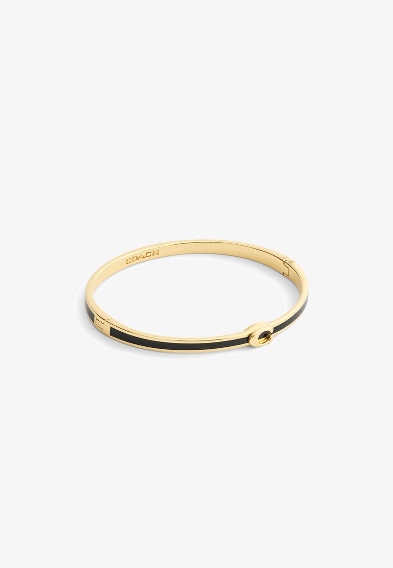 Bracelet jonc doré avec une bande en émail noir et un fermoir circulaire. Présente le nom de la marque gravé sur le côté intérieur.