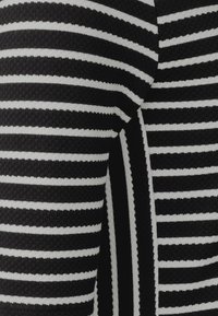 Svart och vit randig tyg med växlande breda och smala ränder, med en mjuk stickad textur och rena kanter.