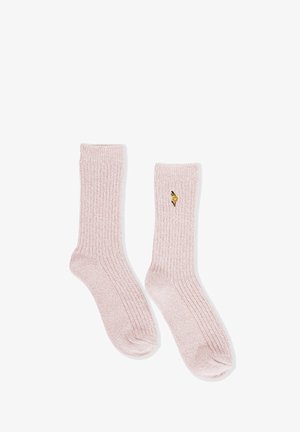 Calcetines de punto acanalado rosa claro con una pequeña flor amarilla bordada en el lado exterior de uno de los calcetines, dispuestos sobre un fondo blanco.