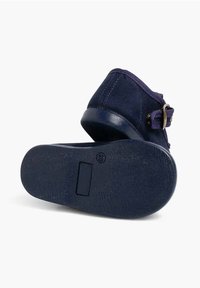 Stivaletto in suede blu navy con punta tonda, dettaglio di cintura decorativa e fibbia, e suola in gomma testurizzata.