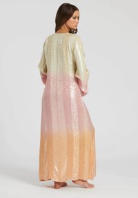 Lange, gradient jurk met glanzende pailletten in gouden, roze en perzik tinten, met een relaxed fit en brede mouwen. Getextureerde stof met verticale lijnen.