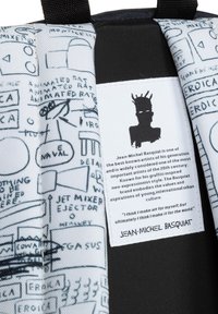 Grafisk ryggsäck med svartvita skisser, inklusive abstrakta former och text. Etiketten framhäver Jean-Michel Basquiats namn och konststil.