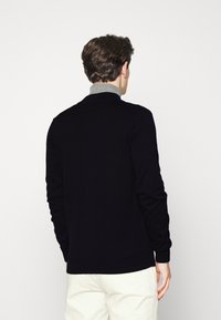 Black knitted sweater with a folded gray collar, ribbed cuffs, and hem. Simple design, no visible patterns or hardware details.
