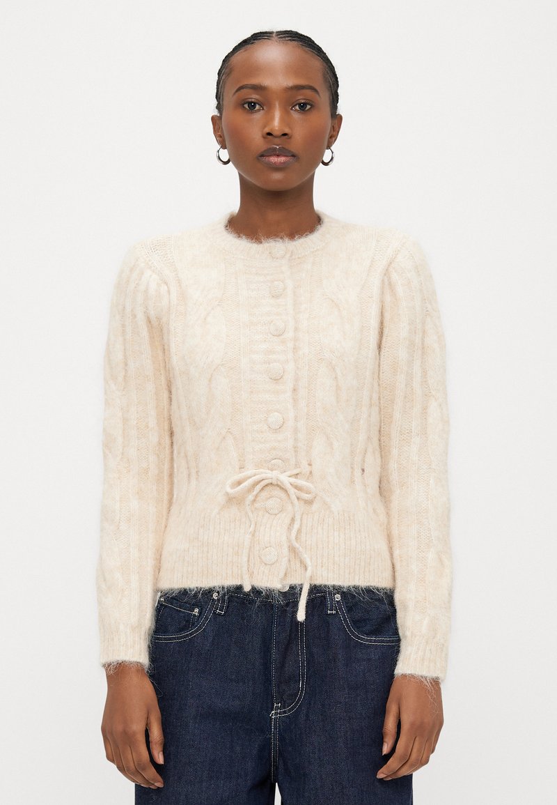 Ελαφρώς μπεζ πλεκτή ζακέτα με στρογγυλεμένο λαιμόκοψη, κουμπιά μπροστά, ριμπ μανσέτες και κορδόνι στη μέση. Μαλακό, υφασμένο υλικό.