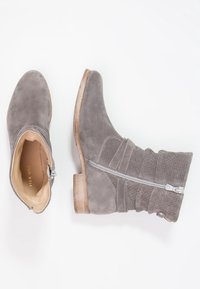 Botas de tobillo de ante gris con punta redondeada, cierre de cremallera y caña texturizada. Cuentan con un tacón de madera y detalles de costura sutiles.