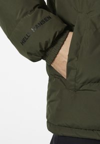 Olijfgroene gewatteerde jas met elastische manchetten en een zijzak, met het "Helly Hansen" logo in het zwart op de mouw.