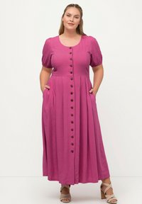 Fuchsiové maxi šaty s krátkými nabíranými rukávy, knoflíkovým zapínáním vpředu a bočními kapsami. Vyrobené z lehkého materiálu s hladkou strukturou.