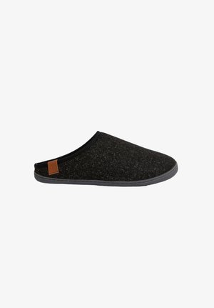 Chausson en laine noire à enfiler avec une surface texturée, semelle en caoutchouc et petit accent en cuir marron sur le côté. Forme lisse et arrondie.