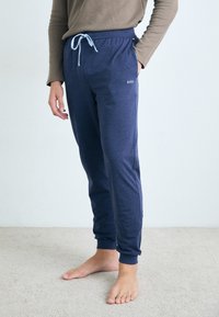 Marineblå joggebukser med snor i livet og sidelommer. Mykt stoff med slim fit og ribbede ankelmansjetter. Logodetalj på låret.