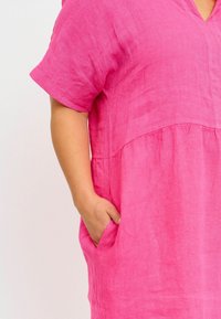 Abito in lino rosa con scollatura a V, maniche corte arrotolate e vita arricciata. Presenta tasche laterali e un tessuto testurizzato.