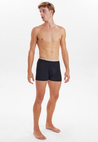 Boxer shorts negros hechos de un material suave y elástico con una cinturilla ceñida. Textura suave y diseño minimalista sin patrones.