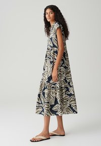 Blumendruck-Midi-Kleid mit dunklem Marine-Hintergrund und cremefarbenen Blättern, ausgestattet mit kurzen Ärmeln und einem gestuften Saum.