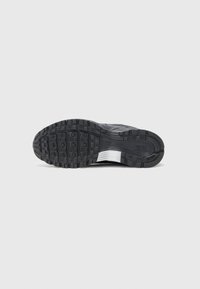 Black athletic shoe with a textured upper and patterned outsole. Features a curved design and a white accent on the midsole.