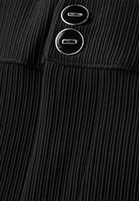 Tessuto a costine nero con due bottoni rotondi neri con accenti argentati posizionati nella parte superiore. La texture è visibile con linee verticali distinte.
