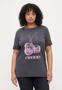 Grå bomulls T-skjorte med en paljett-kirsebærgrafikk i rosa med svarte konturer, og teksten "CHERRY" i fet, uformell skrift.