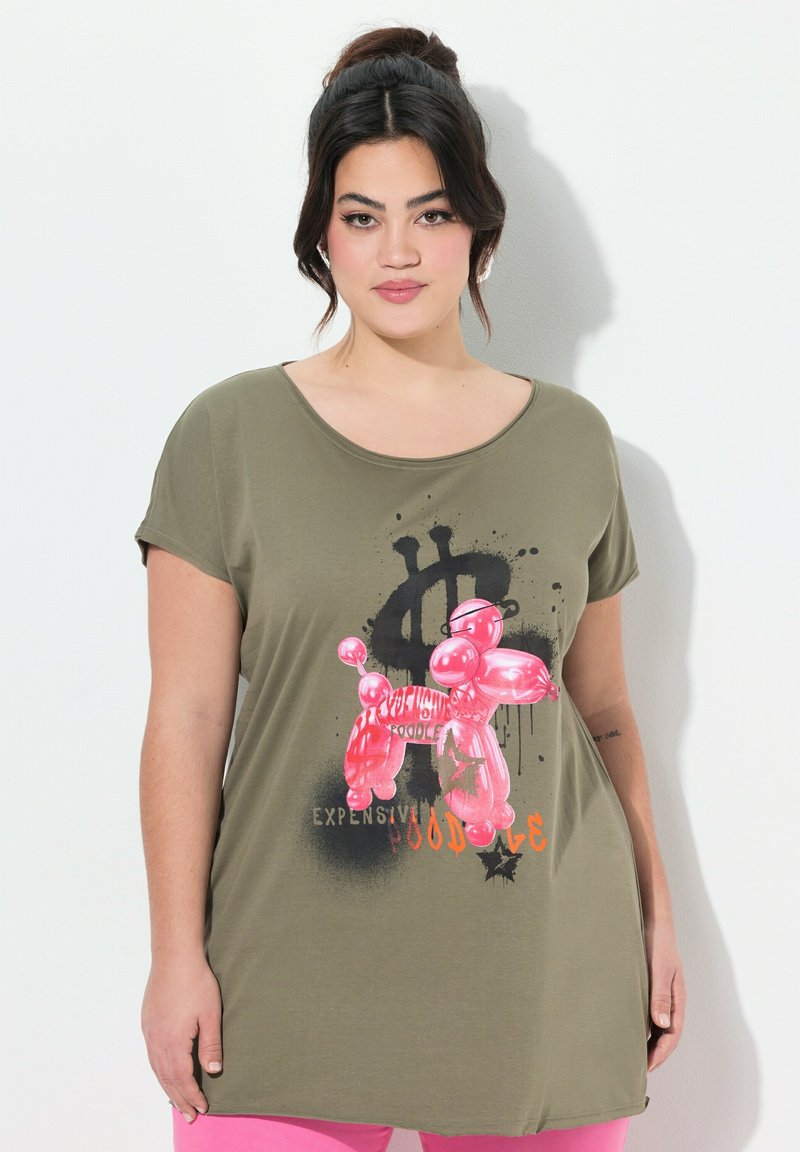 T-shirt vert olive avec un col rond, présentant un graphique de chien en ballon rose et un texte en gras. Manches courtes, coupe décontractée.