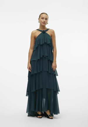 Teal lagd chiffon kjole med halterneck, med volanger og et strømmende design, samt en blomsterdetalje ved halsen.