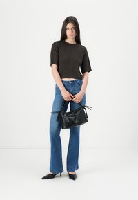 Brun randig crop top, blå utsvängda jeans och en liten svart texturerad handväska med snörning. Svarta spetsiga skor.