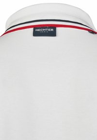 Witte polo met een kraag die een accent heeft van een rode en marineblauwe streep, met een label "HECHTER PARIS" aan de achterkant. Gemaakt van katoen.
