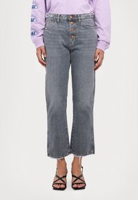 Jeans de mezclilla de tiro alto en un gris claro, con un corte holgado, que cuentan con cierre de cinco botones, dobladillo desflecado y un desgaste mínimo.