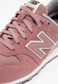 Baskets New Balance 996 roses avec détails en daim et en mesh, logo "N" cousu, et lacets roses sur une semelle blanche et grise.