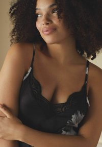 Top negru cu dantelă, având accente florale. Material moale, bretele delicate și o croială lejeră care îmbunătățesc confortul și eleganța.