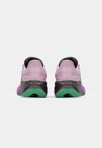 Zapatillas deportivas con parte superior de malla en rosa claro, detalles oscuros y una suela multicolor que incluye verde y morado. Diseño acolchado para mayor comodidad.