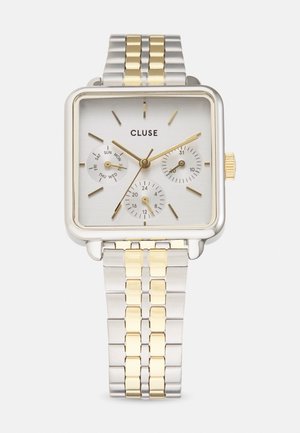 Square silver and gold wristwatch with white dial, three subdials showing day, date, and 24-hour time, and two-tone metal link bracelet.