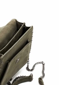 Bolso de mano de ante verde oliva con correa de cadena, que presenta acentos con picos en los laterales y múltiples secciones compartimentadas en su interior.