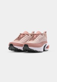 Baskets Nike Air dans un rose doux et crème, avec une tige texturée, une semelle en caoutchouc avec des accents noirs et une unité d'air visible au niveau du talon.