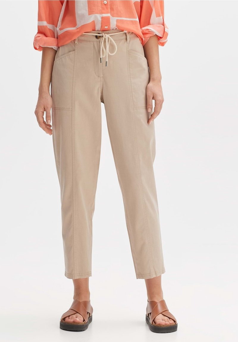 Beige, rechte broek van een katoenmix met een elastische tailleband en voorzakken. Draagt een koraalgestreept shirt en bruine sandalen.