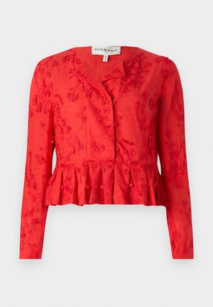 Červená blůza s peplum střihem, dlouhými rukávy, květinovou výšivkou, zapínáním na knoflíky a hladkou texturou. Má mírně uvolněný střih.