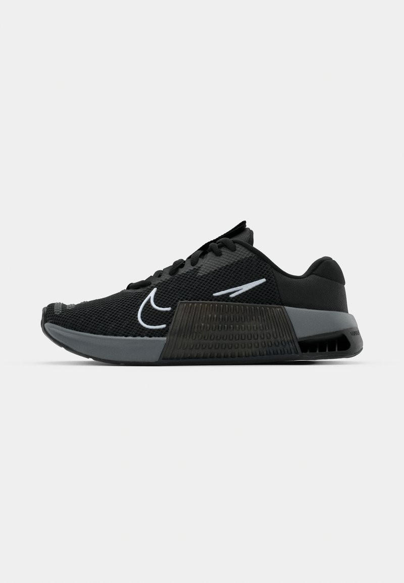 Baskets de sport noires avec une tige en mesh, un stabilisateur de talon gris texturé, un bout arrondi et un accent de logo Swoosh blanc.