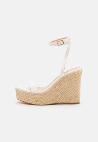 Sandale compensée blanche avec une plateforme en corde texturée, dotée d'une fine bride de cheville et d'un design à bout fermé lisse.