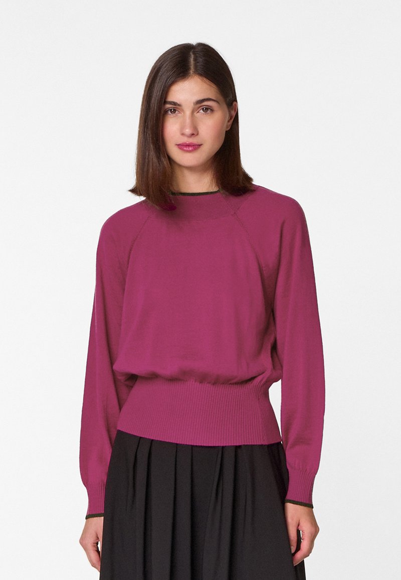 Magenta lange mouwen pullover met een ribgebreide taille en boorden, met een ontspannen pasvorm en een ronde halslijn. Zwarte rok eronder.