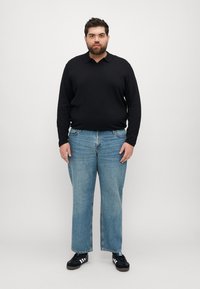 Svart langermet polo skjorte kombinert med lyseblå vide denimjeans. Svart sneakers med hvite striper. Enkel og uformell design.