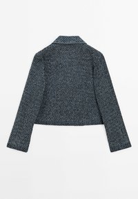 Giacca corta e strutturata in toni di blu scuro e grigio. Presenta un colletto, maniche lunghe e un motivo in tessuto intrecciato senza elementi hardware visibili.