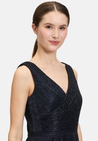 Czarna sukienka z teksturowanej, prążkowanej tkaniny, z dekoltem w kształcie litery V i szerokimi ramiączkami, zaprojektowana w dopasowanej sylwetce.