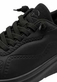 Melnais sporta apavi ar teksturētu ādas virsotni, plakanām melnām auklām, mīkstinātu valni un gludu gumijas zoli ar rakstainu protektoru.